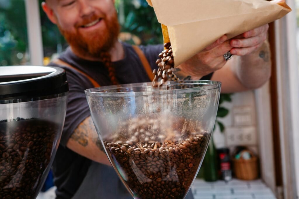 A skilled barista pouring coffee beans into a grinder at a vibrant café.