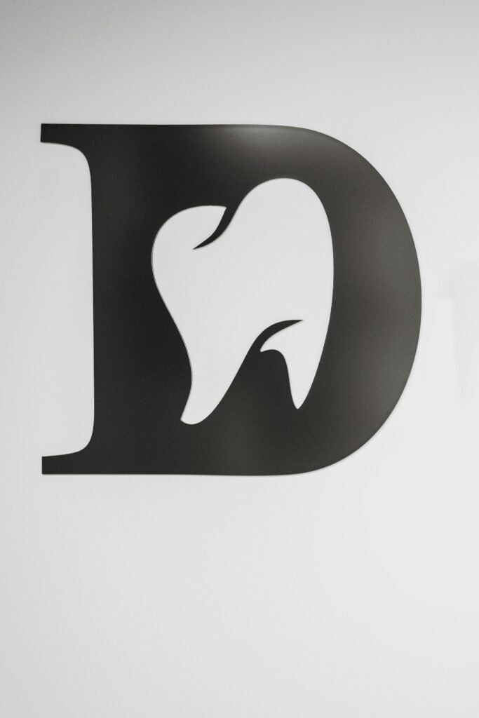 Simple black and white tooth design within letter D, ideal for dental branding.